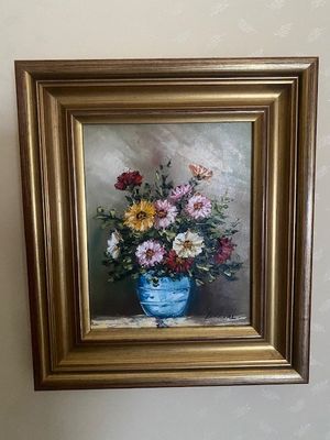 un tableau représentant des fleurs dans un vase bleu, accroché au mur