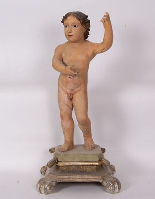 une statue ancienne représentant un garçon sur un socle, la main levée