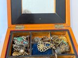 une boîte en bois remplie de bijoux variés, posée sur une surface blanche