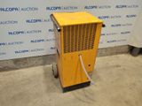 a yellow air conditioner sitting on top of a cement floor next to a wall