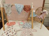 de nombreux vêtements de bébé suspendus à une corde à linge posée sur un lit