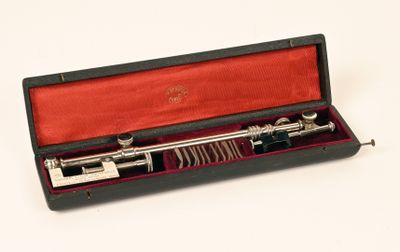 une pipe en argent dans un étui rouge posé sur une surface blanche