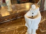 une petite figurine blanche posée sur une table en marbre