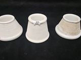 three white vases are lined up on a black surface
