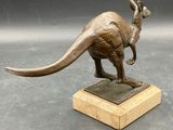 statue of a kangaroo on a wooden base on a gray surface