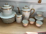 beaucoup d'assiettes et de tasses blanches et dorées sur la table