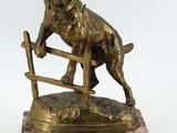 statue en bronze représentant un chien sautant par-dessus une clôture, posée sur un socle en marbre