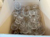 une boîte remplie de gobelets en plastique vides posée sur un sol carrelé