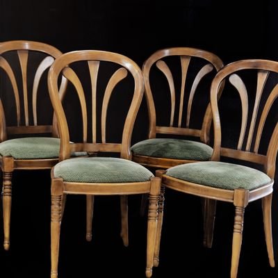 quatre chaises en bois, dotées de coussins rembourrés verts, sont disposées devant un fond noir