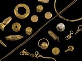 Plusieurs bijoux en or sont exposés sur un fond noir