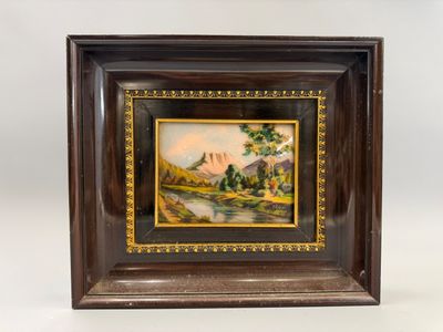 une vieille photo représentant un tableau représentant un paysage de montagne, dans un cadre en bois