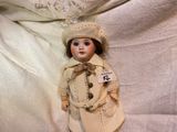 a doll that is wearing a coat and a hat