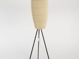 un lampadaire en bois avec un pied trépied noir et un abat-jour beige