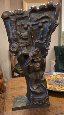 un vase en bronze posé sur une table sur laquelle se trouve une assiette