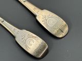 une paire de cuillères en argent ornées de motifs élaborés, posées sur une table