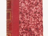 un vieux livre à la couverture rouge posé sur une surface blanche