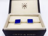 a close up of a pair of blue cufflinks in a box