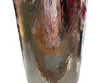 a silver vase that is sitting on a white surface