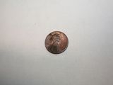 a close up of a penny sitting on a white surface