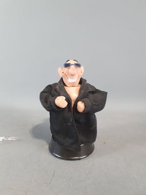 une figurine représentant un homme vêtu d'une veste noire et portant des lunettes de soleil