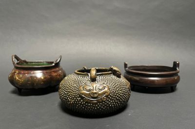 three bronze pots with handles and handles sitting next to each other