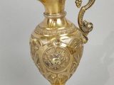 a gold vase with a dragon handle on a table