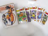 several dragon ball cards are on a table next to a book