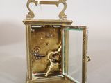a small brass clock with a glass door on it