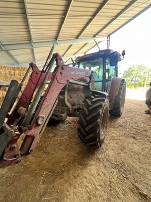 un tracteur garé dans une grange où il y a du foin par terre