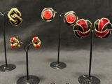 six pairs of earrings are displayed on black stands on a gray surface