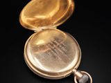 an antique gold pocket watch with a chain hanging from it ' s side