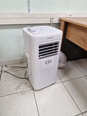 un petit climatiseur posé par terre à côté d'un bureau
