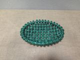 a close up of a green beaded bracelet on a table