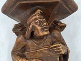 une statue représentant un homme tenant une boîte sur la tête
