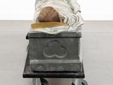 a sculpture of a person laying in a bed on a cart