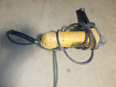 une perceuse électrique jaune et noire posée par terre