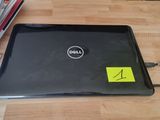 un ordinateur portable Dell, sur lequel est collé un autocollant, posé sur une table