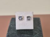 a pair of diamond earrings sitting on top of a marble block