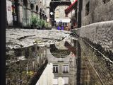 a reflection of a building in a puddle of water