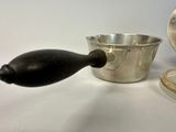 a silver cup and a silver spoon sitting on a table