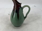 a green and brown pitcher on a white surface