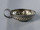 a silver bowl with a handle on a gray surface