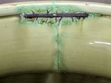 a close up of a green toilet bowl with a rusted edge
