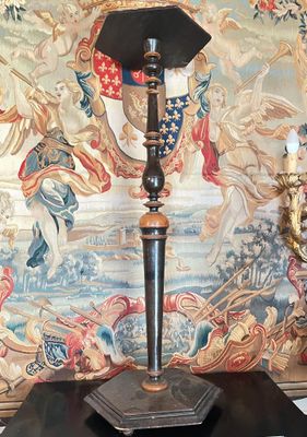 une lampe posée sur une table devant une tapisserie
