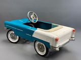une voiture à pédales à l'ancienne avec un volant, sur fond gris