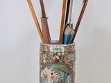a vase with umbrellas and pens in it on a table