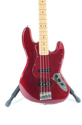 an image of a red bass guitar on a stand on a white background