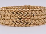 a close up of a gold bracelet on a white surface