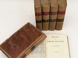 several old books sitting on top of each other on a white surface