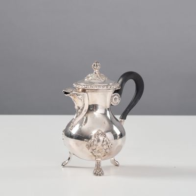 une cafetière en argent avec une poignée noire posée sur une table